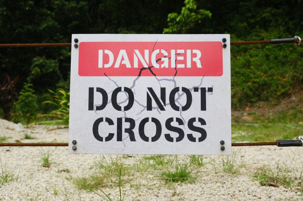 A picture of danger do not cross sign at gate.